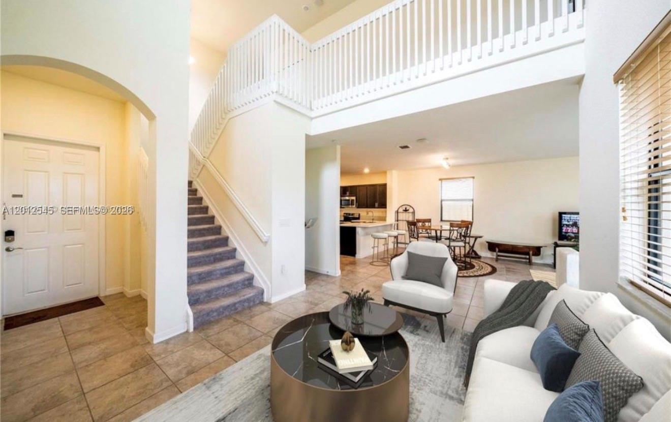 A two-story living room features a staircase, tiled floors, and an open-concept kitchen area — 2401 NE 2nd Dr, Homestead FL 33033, HOMESTEAD, FL