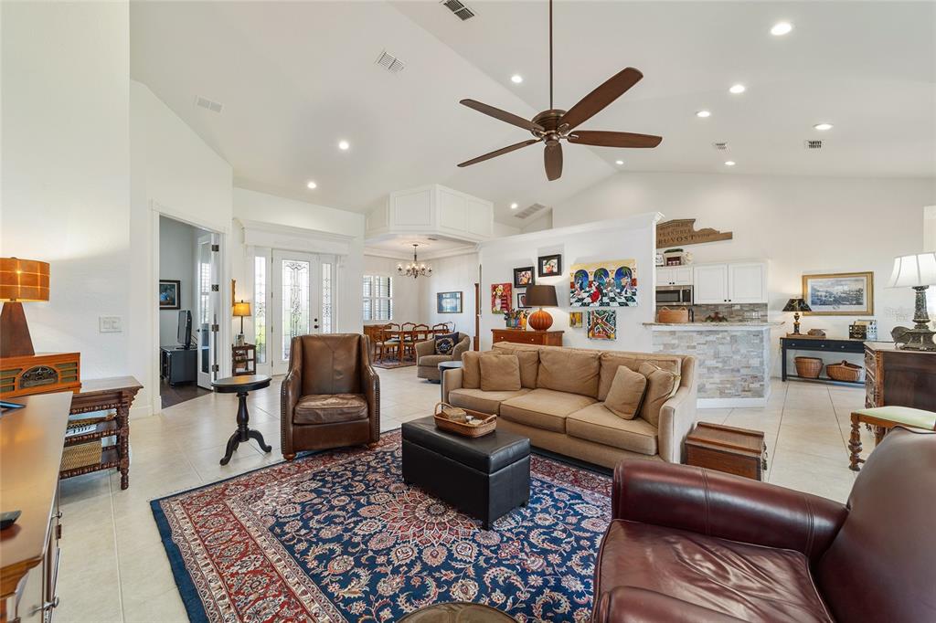 A spacious living room with vaulted ceilings, a large area rug, and an open kitchen — 2806 SE 30TH STREET, OCALA, FL