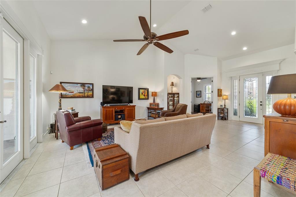 A living room with a vaulted ceiling, tile floors, a beige sofa, and a television — 2806 SE 30TH STREET, OCALA, FL