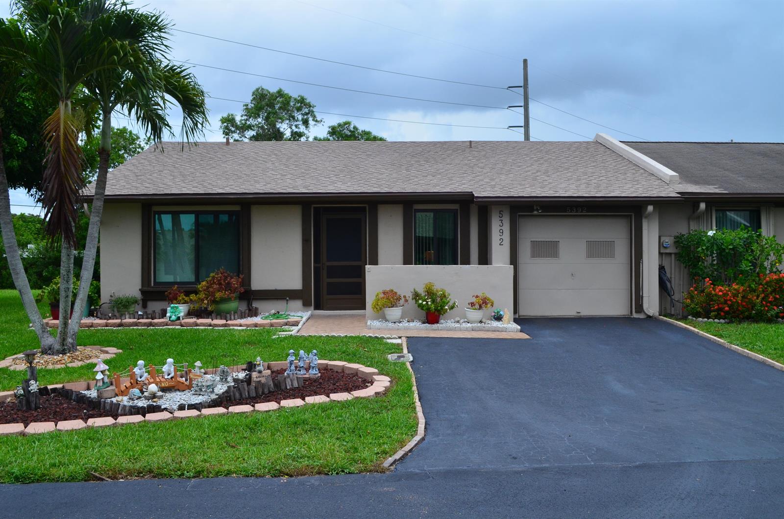 A single-story house features a tan exterior, a one-car garage, and a landscaped front yard — 5392 Viburnum Circle, Delray Beach FL 33484, DELRAY BEACH, FL