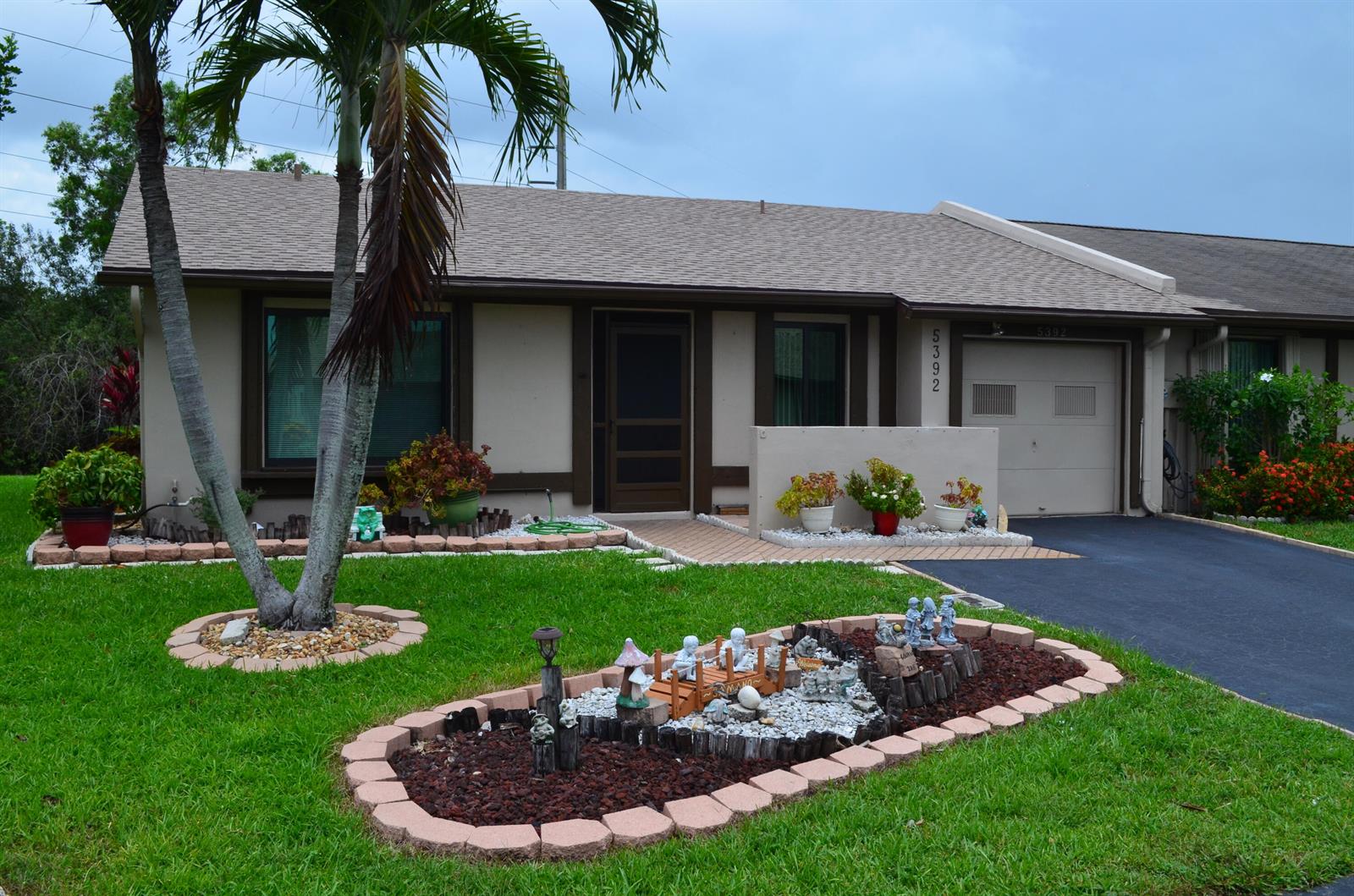 A single-story house with a palm tree, a landscaped garden bed, and an attached garage — 5392 Viburnum Circle, Delray Beach FL 33484, DELRAY BEACH, FL
