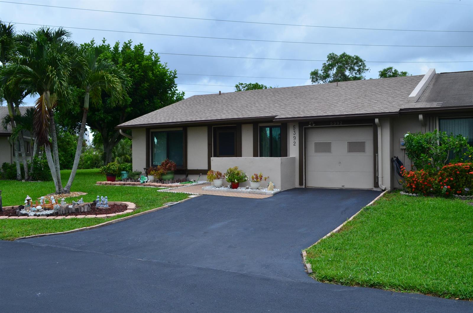 A single-story house with a tan exterior, a paved driveway, and a small front garden — 5392 Viburnum Circle, Delray Beach FL 33484, DELRAY BEACH, FL