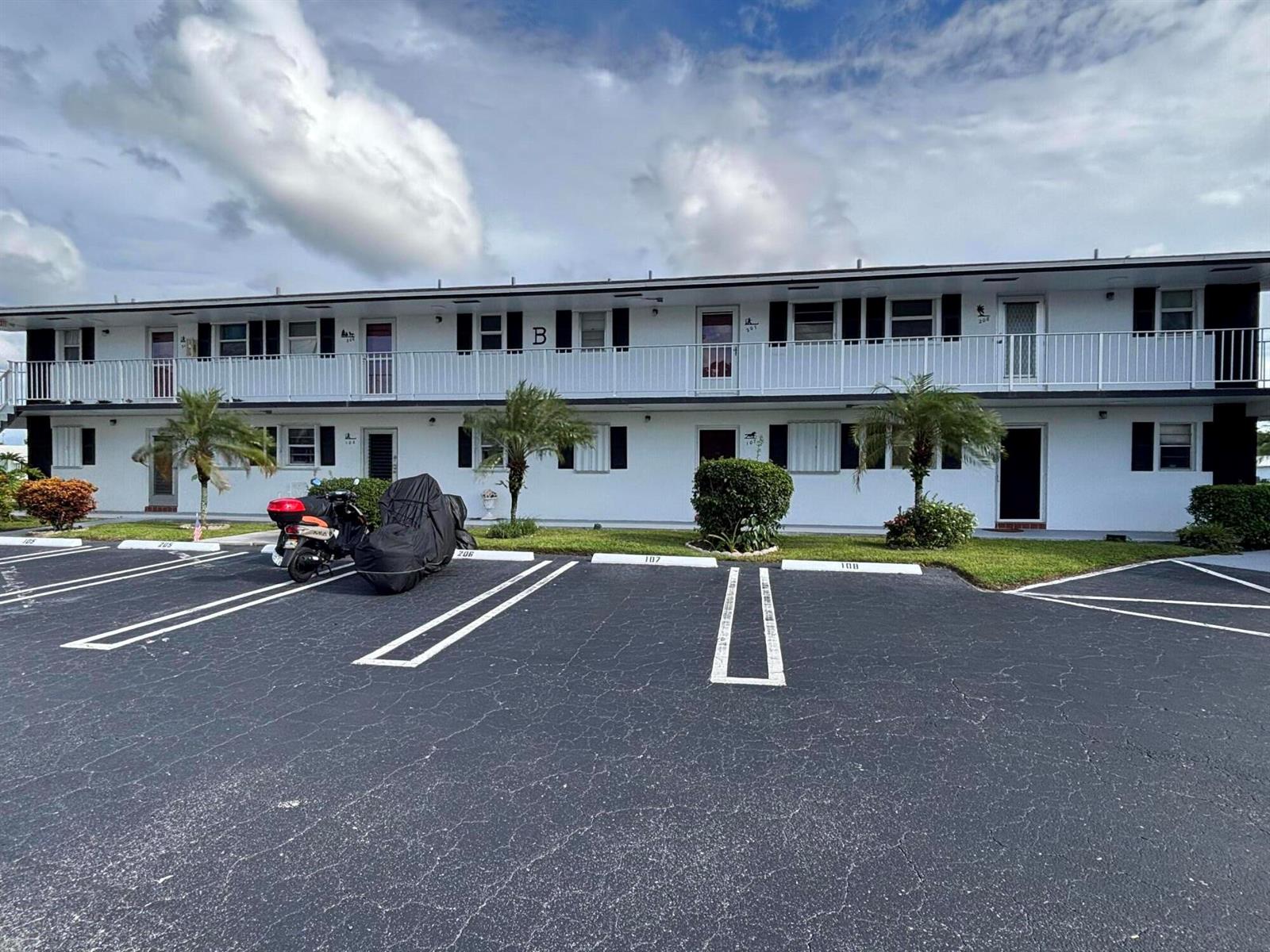 A two-story white apartment building with a parking lot in the foreground — 1112 Lake Terrace # 207, Boynton Beach FL 33426, BOYNTON BEACH, FL
