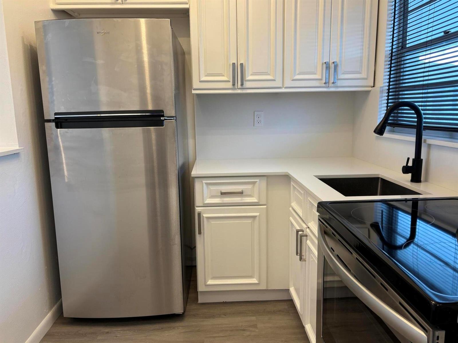 A kitchen featuring white cabinets, stainless steel appliances, a black faucet, and white countertops — 1112 Lake Terrace # 207, Boynton Beach FL 33426, BOYNTON BEACH, FL