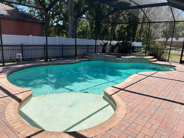A screened-in swimming pool with a spa and brick paver patio in a backyard — 22444 OAKVILLE DRIVE, LAND O LAKES, FL