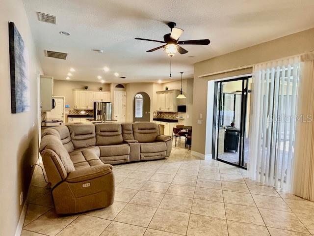A spacious living room features a large sectional sofa, tile flooring, and a ceiling fan — 22444 OAKVILLE DRIVE, LAND O LAKES, FL