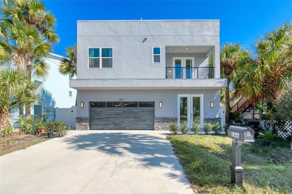 A two-story modern house with a gray stucco exterior, a garage, and a second-floor balcony — 206 N HALIFAX AVENUE, DAYTONA BEACH, FL