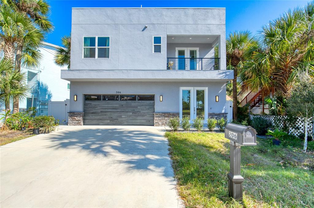 A two-story modern house with a gray stucco exterior, a wood-paneled garage, and a balcony — 206 N HALIFAX AVENUE, DAYTONA BEACH, FL