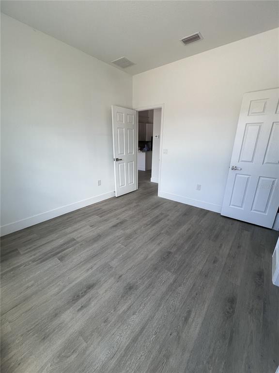 An empty room with gray wood-look flooring, white walls, and two white interior doors — 1782 CORIANDER DRIVE, POINCIANA, FL