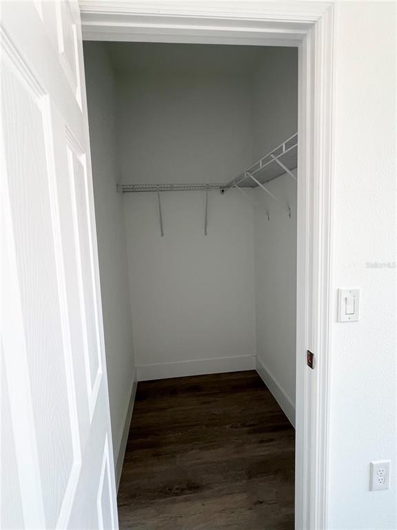 A walk-in closet features white walls, dark wood-look flooring, and wire shelving — 1782 CORIANDER DRIVE, POINCIANA, FL
