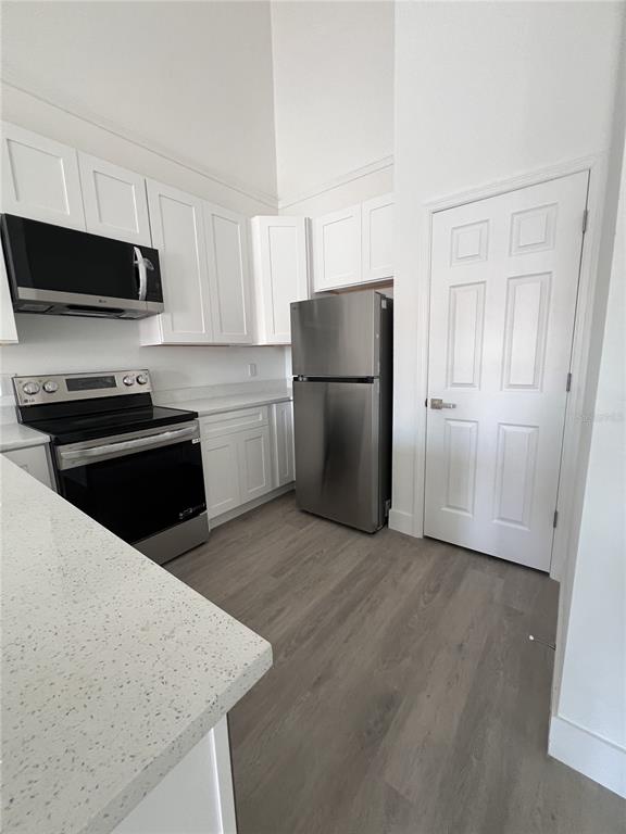 A kitchen features white cabinets, stainless steel appliances, and light-colored countertops — 1782 CORIANDER DRIVE, POINCIANA, FL