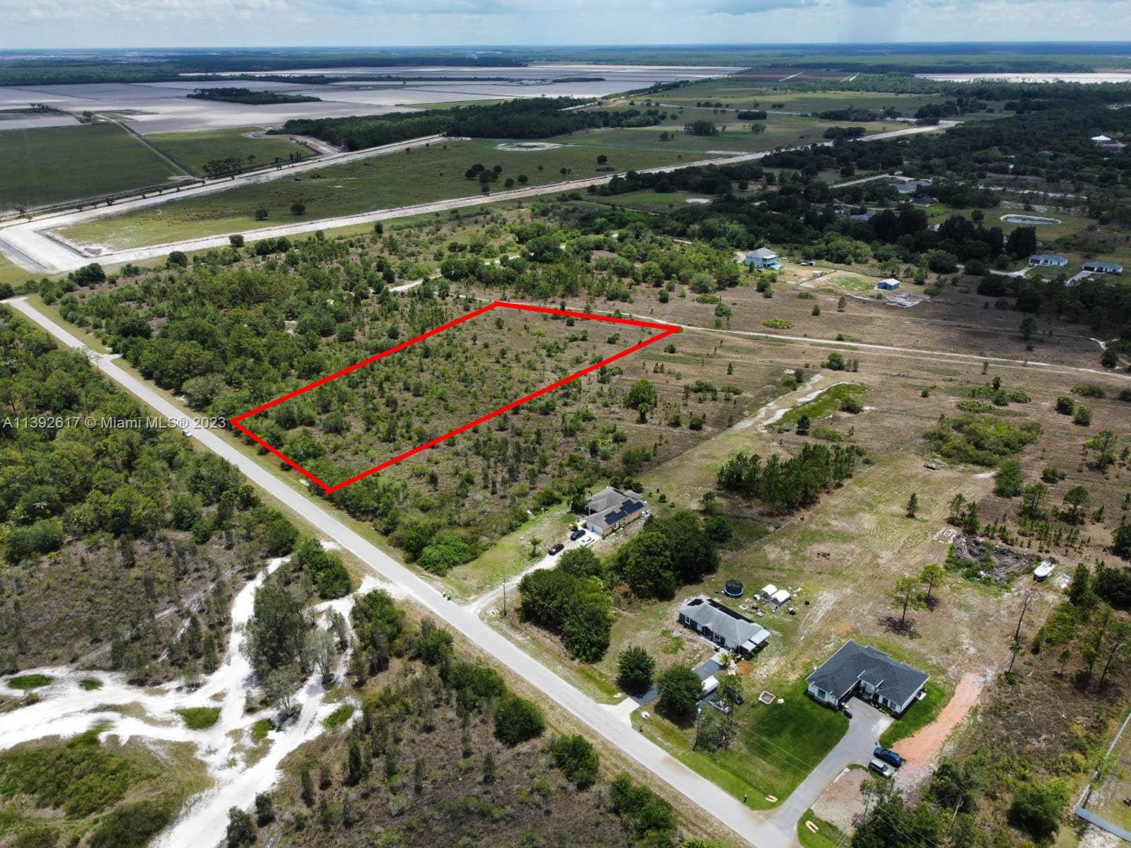 An aerial view shows a rectangular plot of land outlined in red near a road — 0 0, Naples FL 34120, NAPLES, FL