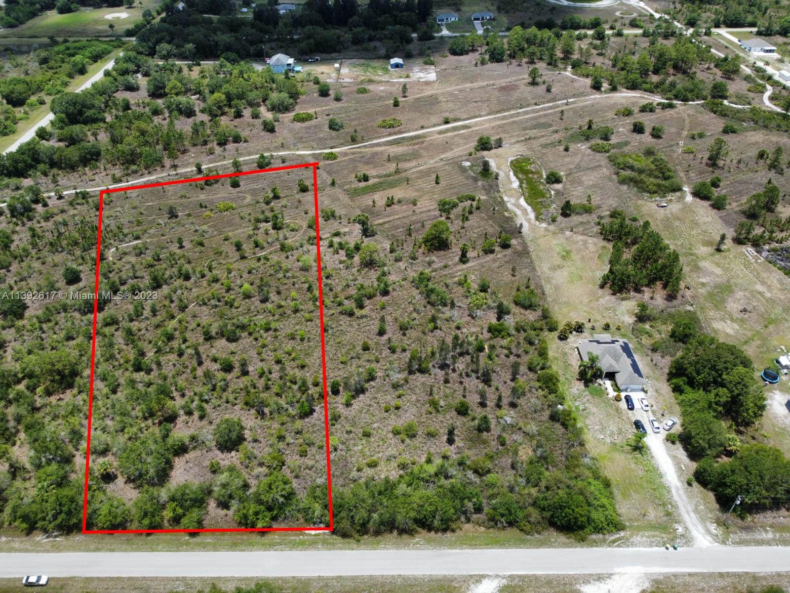 An aerial view shows a rectangular plot of undeveloped land outlined in red near a road — 0 0, Naples FL 34120, NAPLES, FL