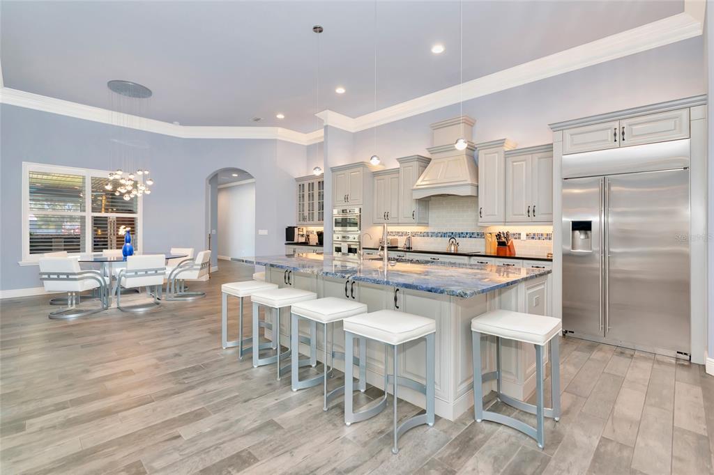 A kitchen with a blue granite island, white stools, light gray cabinets, and wood-look flooring — 28154 GOPHER HILL ROAD, MYAKKA CITY, FL