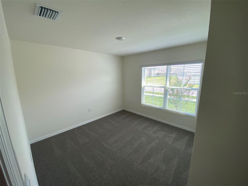 An empty bedroom features gray carpeting, off-white walls, and a window with white blinds — 4961 SW 88TH PLACE, OCALA, FL