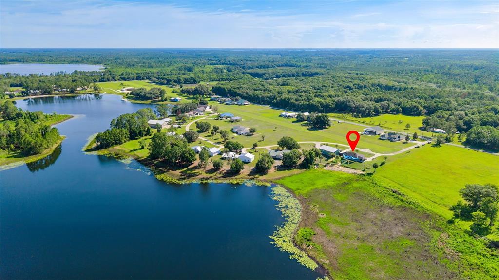 An aerial view shows a house with a red map pin near a large lake — 107 EAGLES NEST LANE, CRESCENT CITY, FL