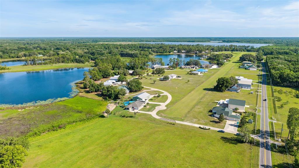 An aerial view shows a rural residential property with a grass airstrip and several lakes — 107 EAGLES NEST LANE, CRESCENT CITY, FL