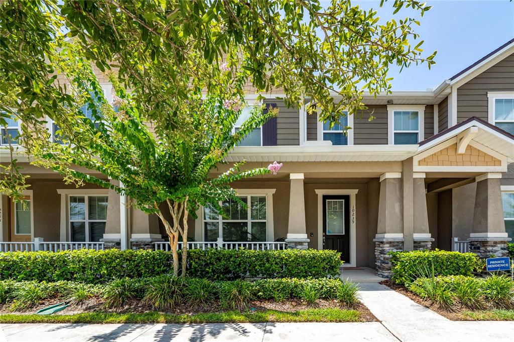 A two-story townhouse exterior features a covered front porch, stone accents, and a landscaped yard — 10239 HIGHLINE CREST STREET, ORLANDO, FL