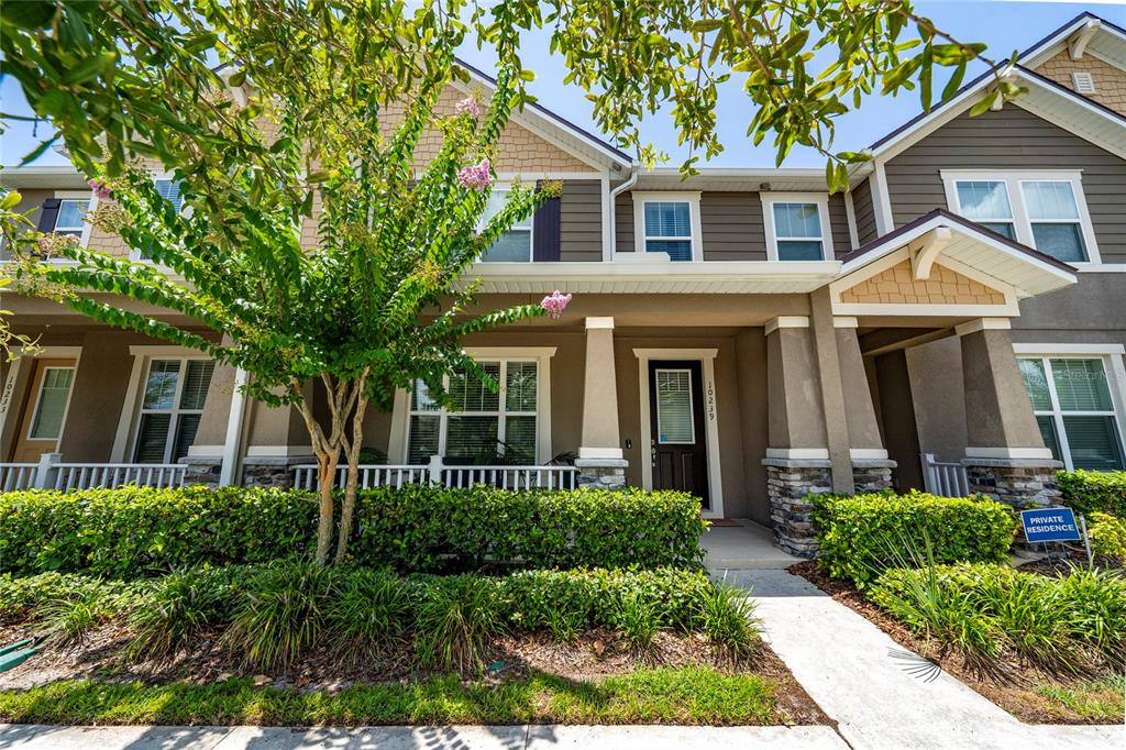 A two-story townhouse exterior features a stone-accented porch, a small front yard, and landscaping — 10239 HIGHLINE CREST STREET, ORLANDO, FL