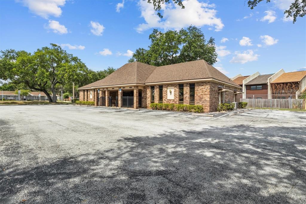 A single-story brick commercial building with a large asphalt parking lot in the foreground — 4945 SOUTHFORK DRIVE, LAKELAND, FL