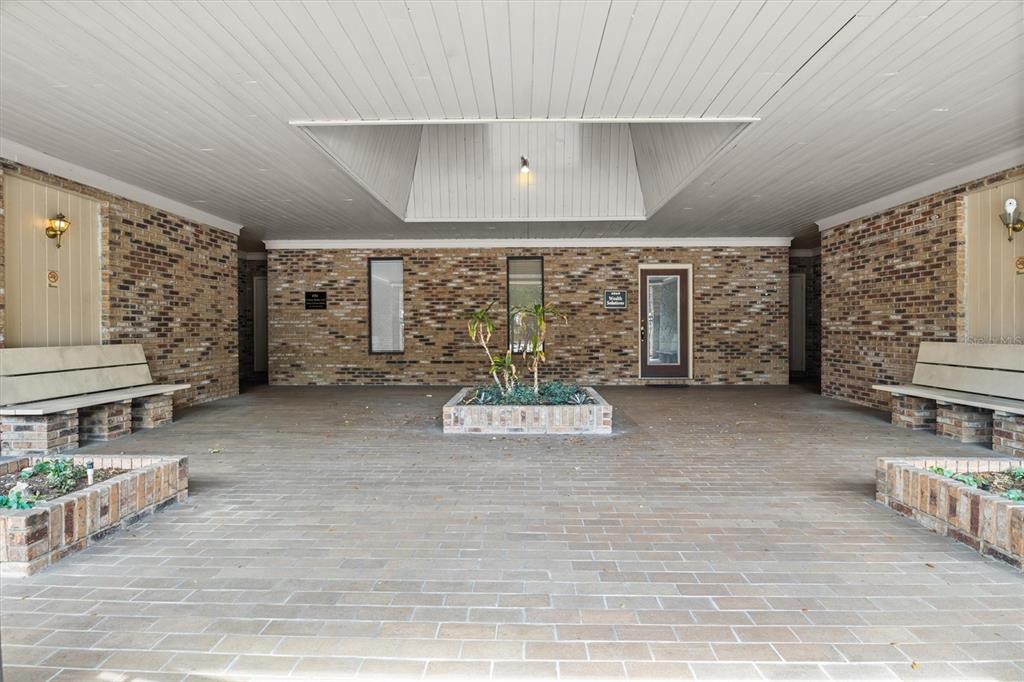 A covered brick entryway features built-in benches, a central planter, and a recessed ceiling light — 4945 SOUTHFORK DRIVE, LAKELAND, FL