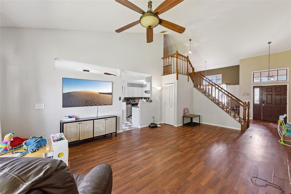 A living room with wood flooring, a staircase, a ceiling fan, and a wall-mounted television — 1513 OBERLIN TERRACE, LAKE MARY, FL