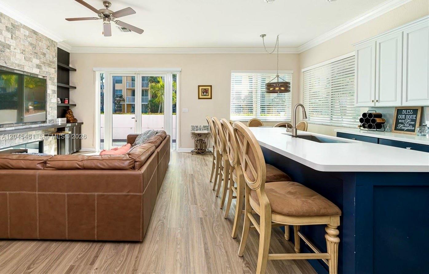 A kitchen with a blue island and bar stools overlooks a living area with a sofa — 208 SE 15th St, Dania Beach FL 33004, DANIA BEACH, FL