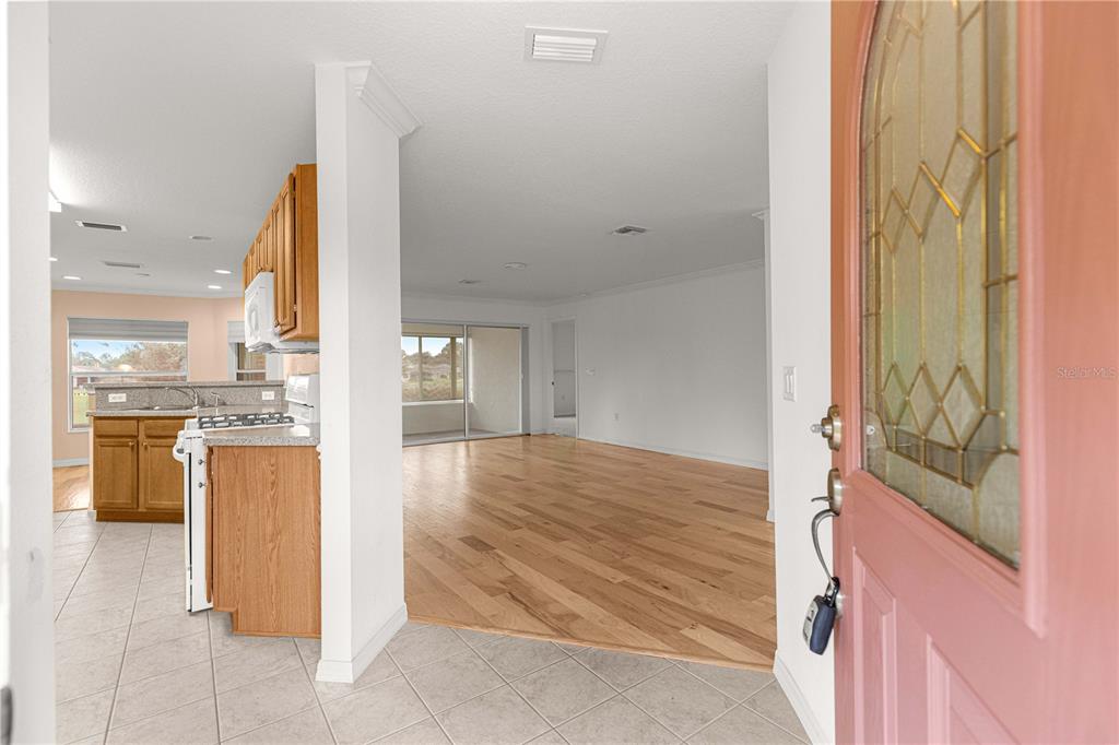 An entryway opens into a kitchen with tile floors and a living area with wood flooring — 9119 SW 99TH COURT ROAD, OCALA, FL