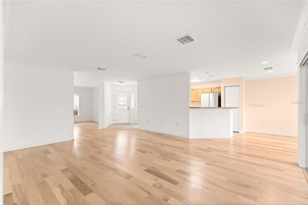 An open-concept living area features light wood flooring, white walls, and a kitchen breakfast bar — 9119 SW 99TH COURT ROAD, OCALA, FL