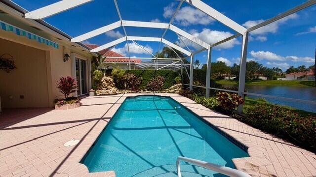A screened-in swimming pool sits on a brick patio overlooking a lake — 7240 Deer Point Lane, West Palm Beach FL 33411, WEST PALM BEACH, FL