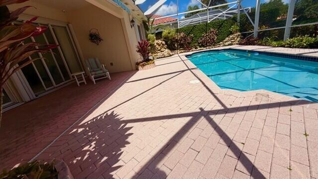 A patio with brick pavers features a swimming pool enclosed by a screen cage — 7240 Deer Point Lane, West Palm Beach FL 33411, WEST PALM BEACH, FL