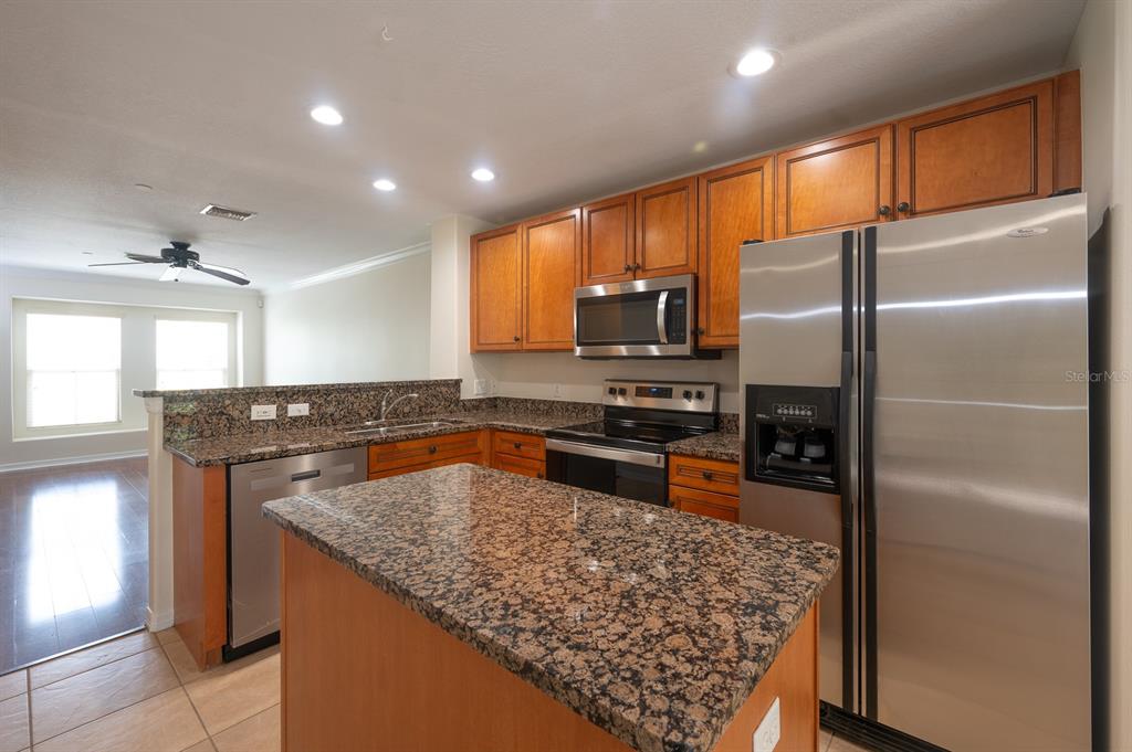 A kitchen features wood cabinets, granite countertops, stainless steel appliances, and a central island — 8860 WHITE SAGE LOOP, BRADENTON, FL