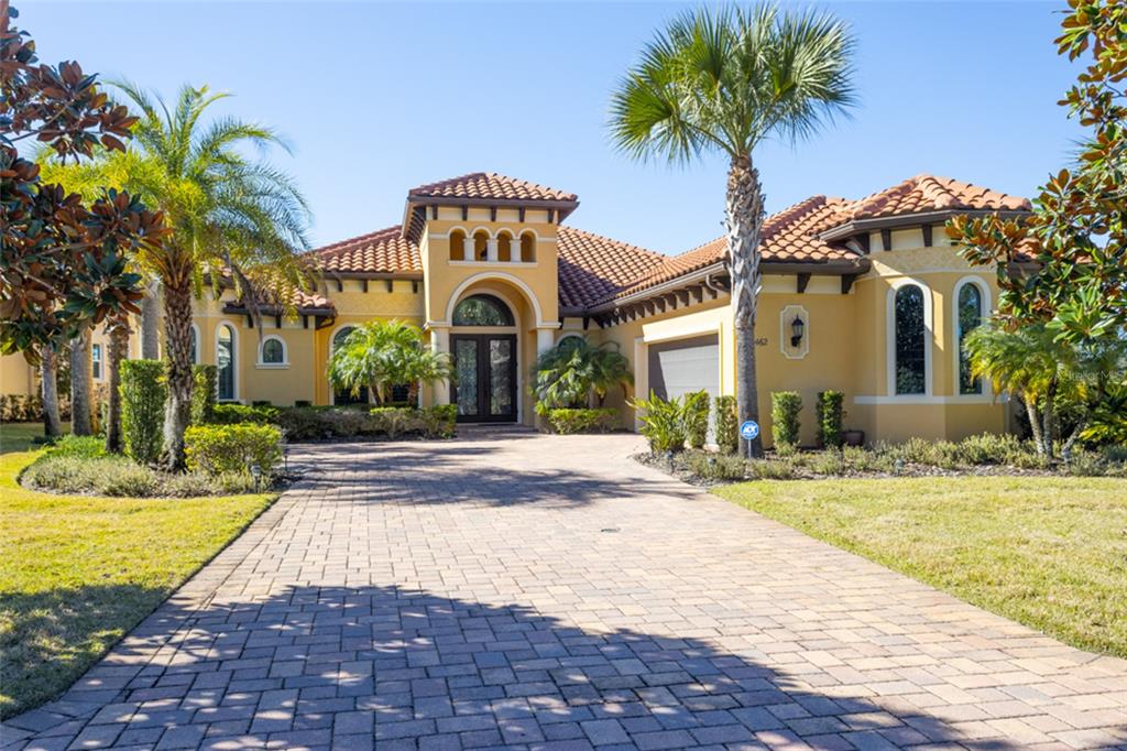 A single-story Mediterranean-style house with a tile roof, yellow stucco exterior, and paved driveway — 462 SWEETGUM LANE, PALM COAST, FL