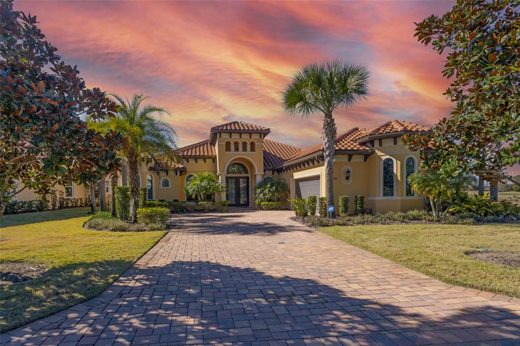 A Mediterranean-style house with a tile roof and paver driveway under a sunset sky — 462 SWEETGUM LANE, PALM COAST, FL