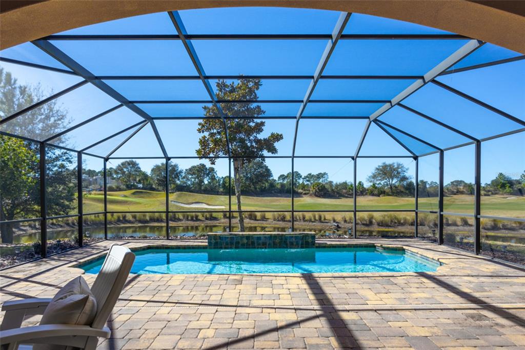 A screened-in pool patio overlooks a pond and golf course on a sunny day — 462 SWEETGUM LANE, PALM COAST, FL