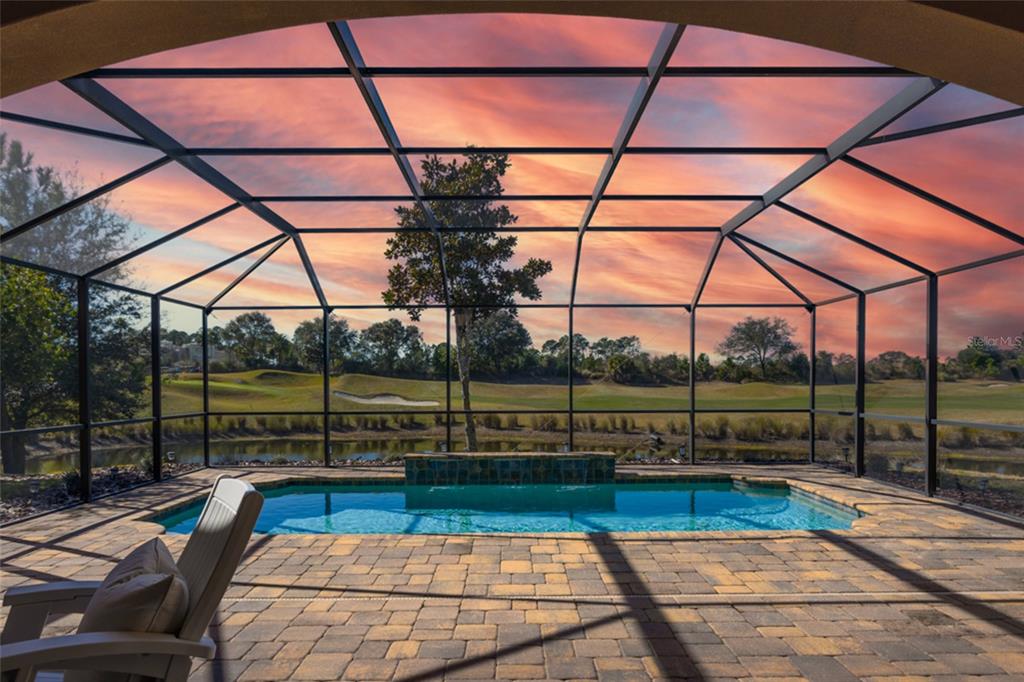 A screened-in pool patio overlooks a pond and golf course at sunset — 462 SWEETGUM LANE, PALM COAST, FL