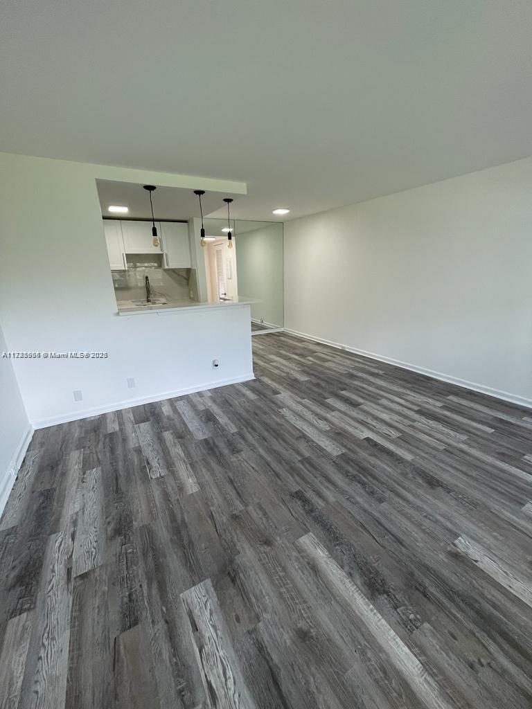 An open-concept living area features gray wood-look flooring and a kitchen with a breakfast bar — 22 Suffolk A # 22, Boca Raton FL 33434, BOCA RATON, FL