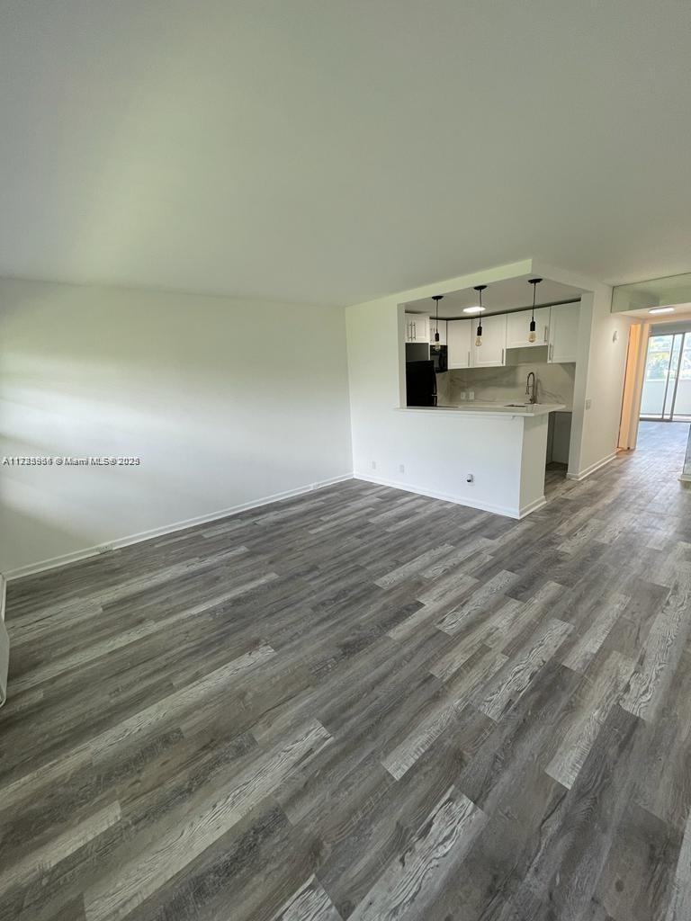 An open-concept living area features light gray wood-look flooring and a kitchen with white cabinets — 22 Suffolk A # 22, Boca Raton FL 33434, BOCA RATON, FL