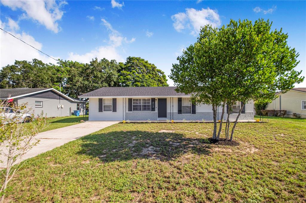 A single-story house with a white facade, gray brick base, and a concrete driveway — 2112 EMBRY AVENUE, HAINES CITY, FL