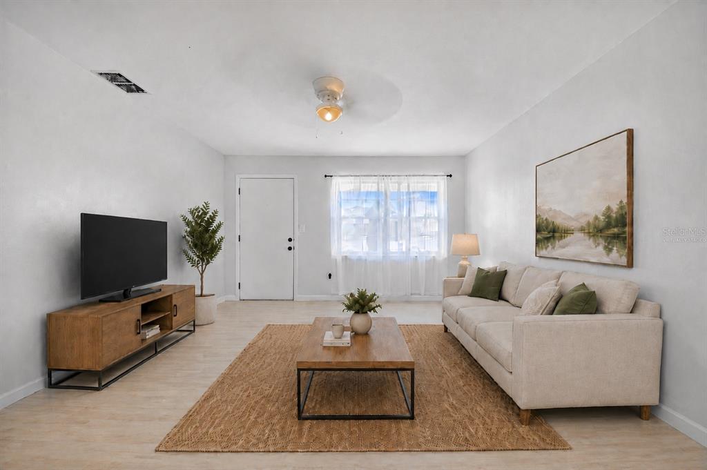 A living room features a beige sofa, wooden coffee table, media console, and a jute rug — 2112 EMBRY AVENUE, HAINES CITY, FL