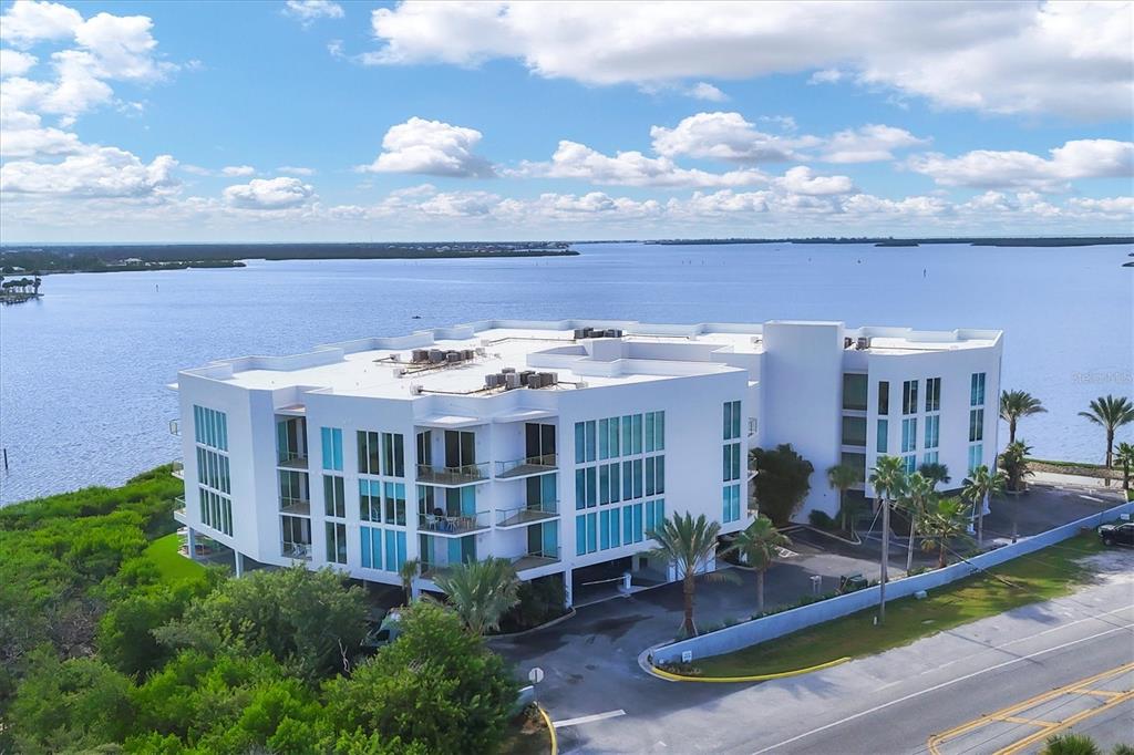 An aerial view of a white multi-story apartment building situated along a waterfront — 1375 BEACH ROAD UNIT 311, ENGLEWOOD, FL