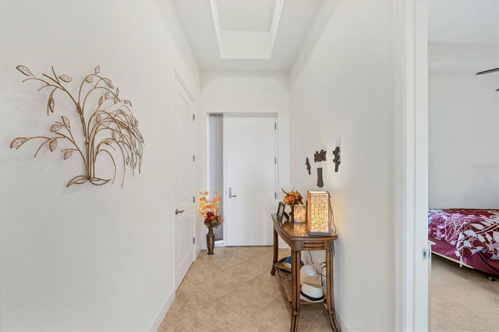 A bright entryway features tile flooring, a tray ceiling, a console table, and wall decor — 1375 BEACH ROAD UNIT 311, ENGLEWOOD, FL