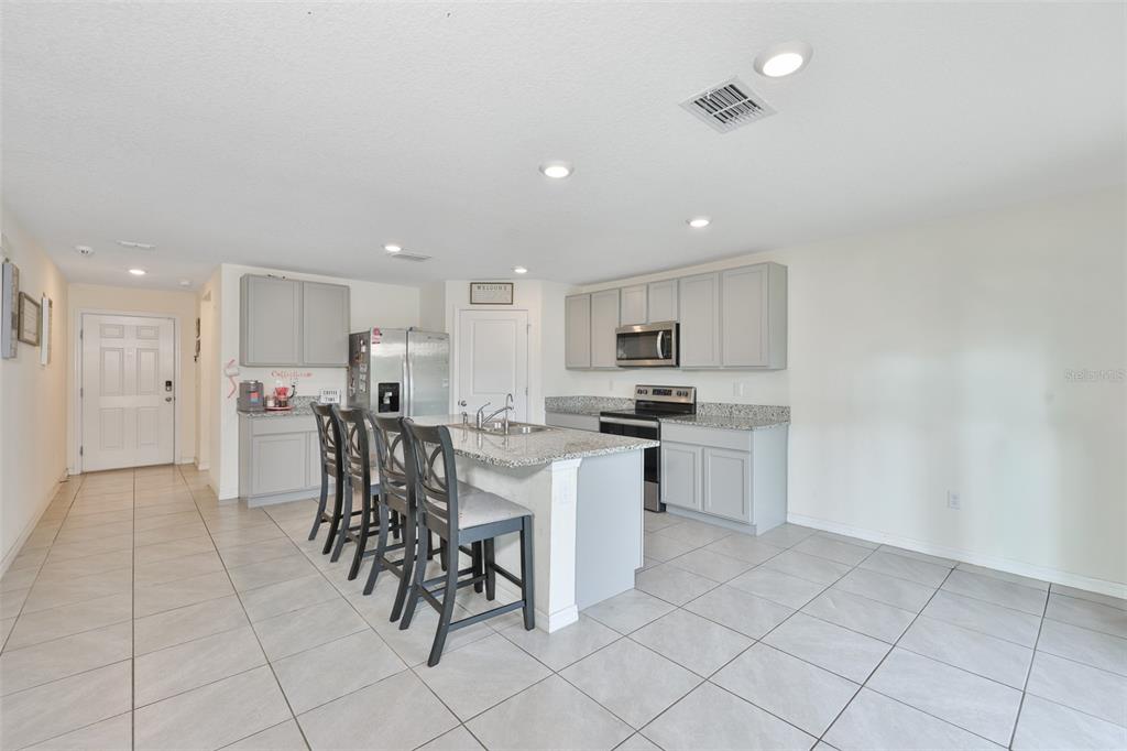 A kitchen with gray cabinets, granite countertops, a center island, and light-colored tile flooring — 5244 FIDDLE FIG AVENUE, WIMAUMA, FL