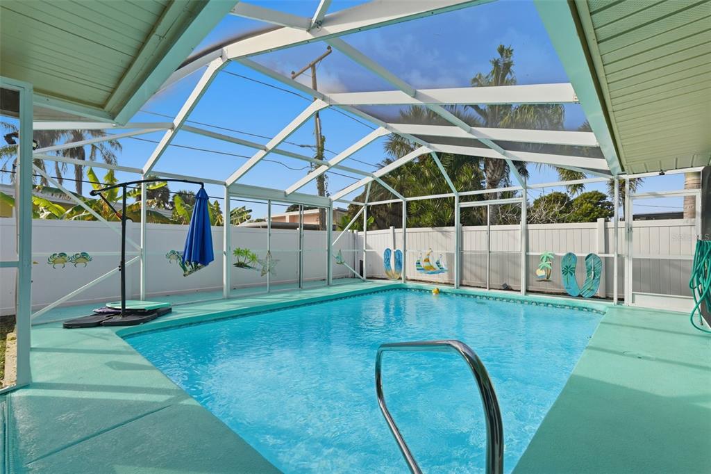 A swimming pool enclosed by a white metal screen structure with a painted concrete deck — 3944 49TH AVENUE S, ST PETERSBURG, FL