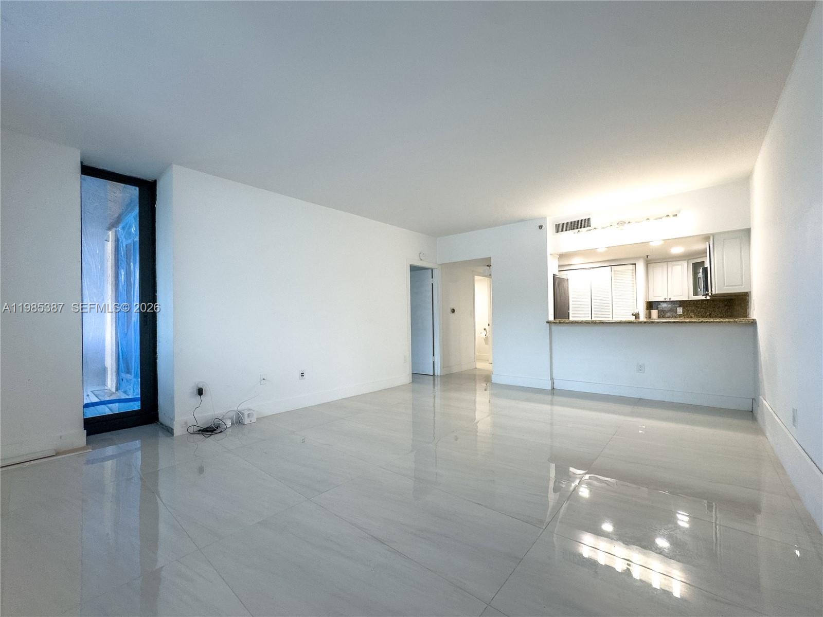 A living room with white walls, glossy tile flooring, and an open kitchen pass-through — 540 Brickell Key Dr # 416, Miami FL 33131, MIAMI, FL