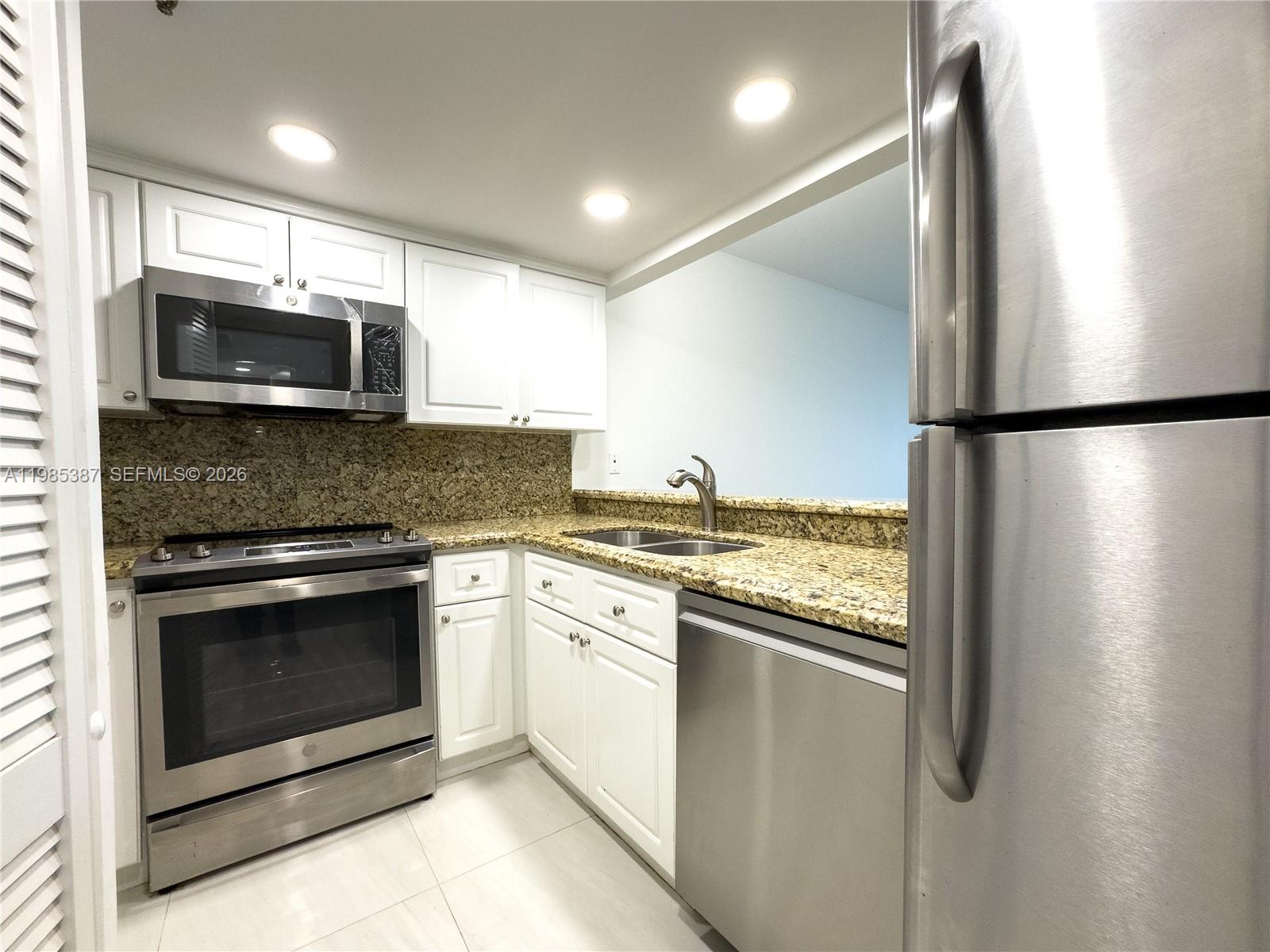 A kitchen features white cabinets, granite countertops, and stainless steel appliances — 540 Brickell Key Dr # 416, Miami FL 33131, MIAMI, FL