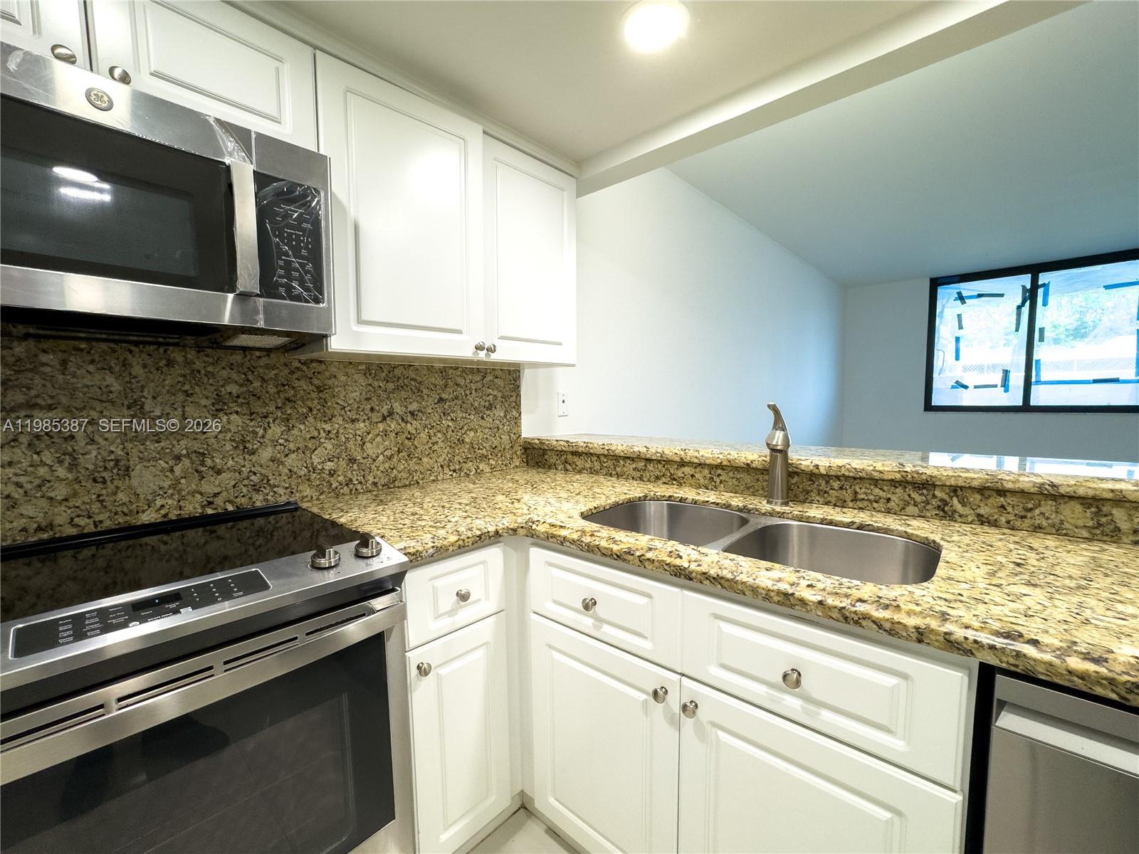 A kitchen features white cabinets, granite countertops, stainless steel appliances, and a double sink — 540 Brickell Key Dr # 416, Miami FL 33131, MIAMI, FL