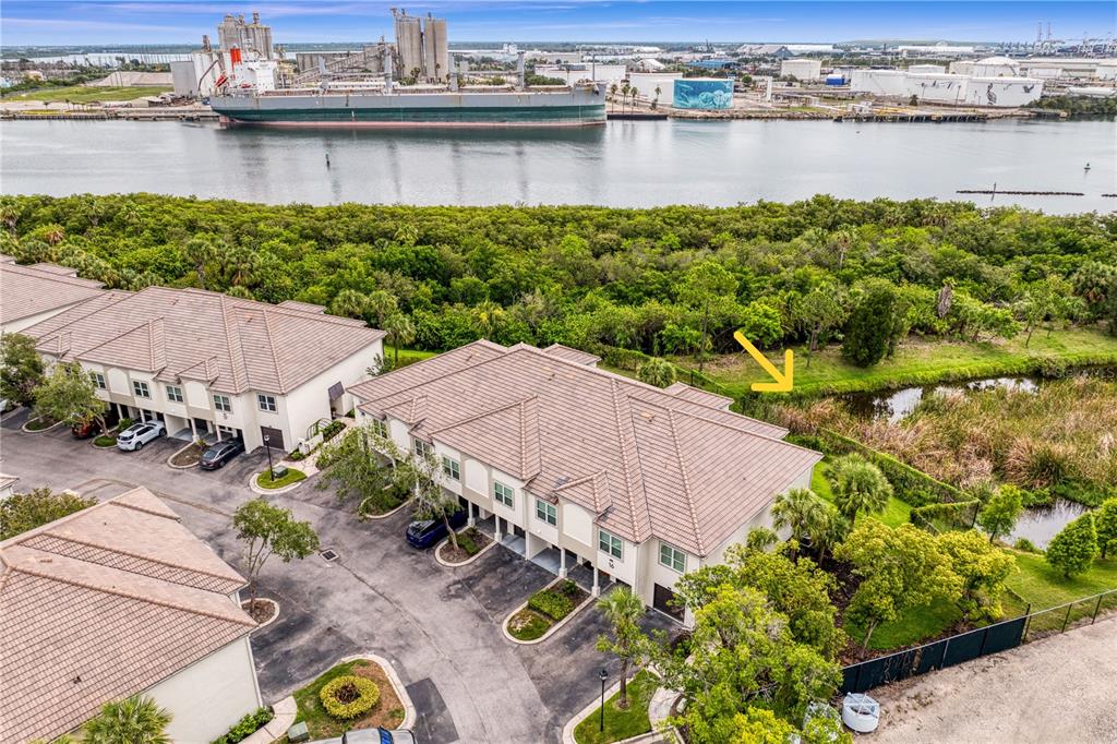 An aerial view shows townhouses near a waterway with a large cargo ship docked nearby — 919 NORMANDY TRACE ROAD, TAMPA, FL