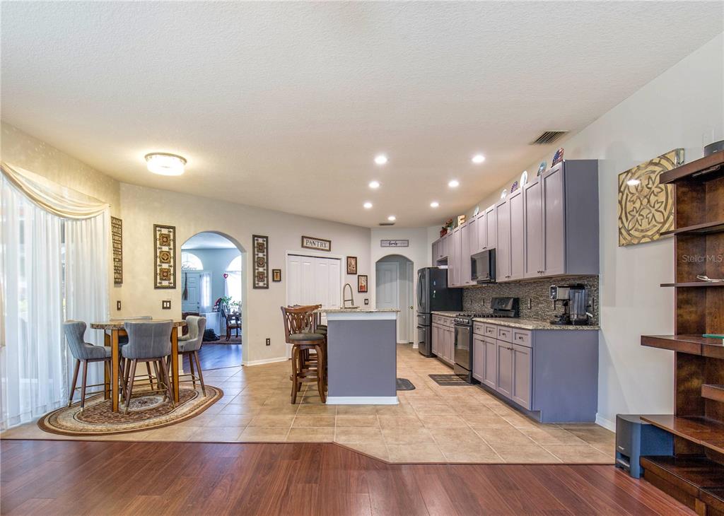 A kitchen with gray cabinets, a center island, and tile flooring adjacent to a dining area — 1422 TAWNYBERRY COURT, TRINITY, FL