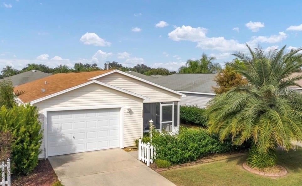A single-story house with light siding, a garage, and a palm tree in the front yard — 1037 RIDGEVILLE ROAD, THE VILLAGES, FL